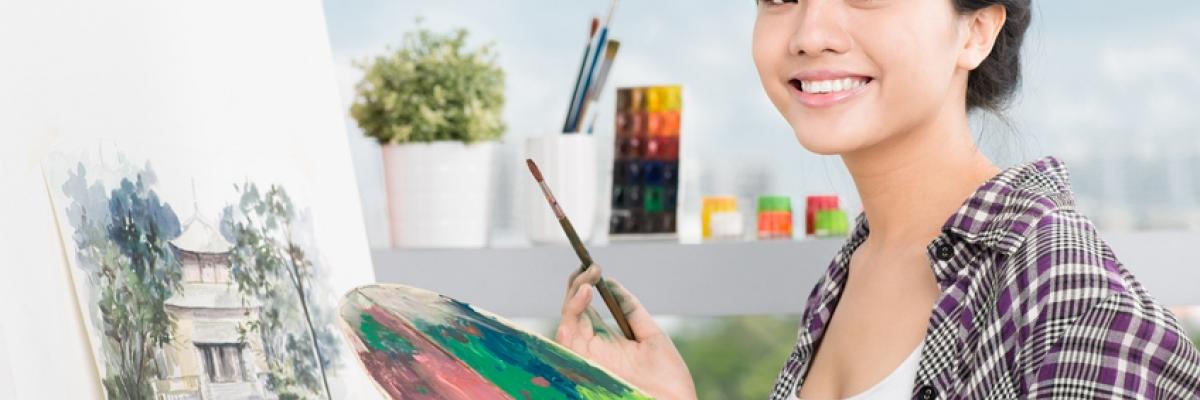 Student artist smiling with paint brush and paint palette