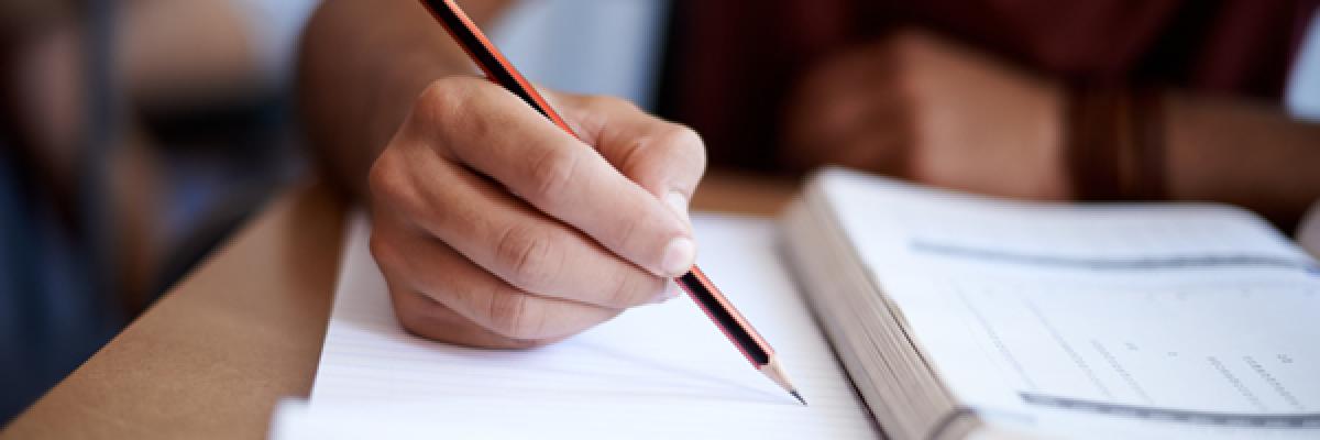 Closeup shot of a young man writing on a note pad